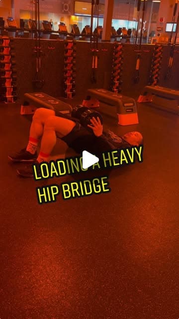 Loading a heavy dumbbell hip bridge